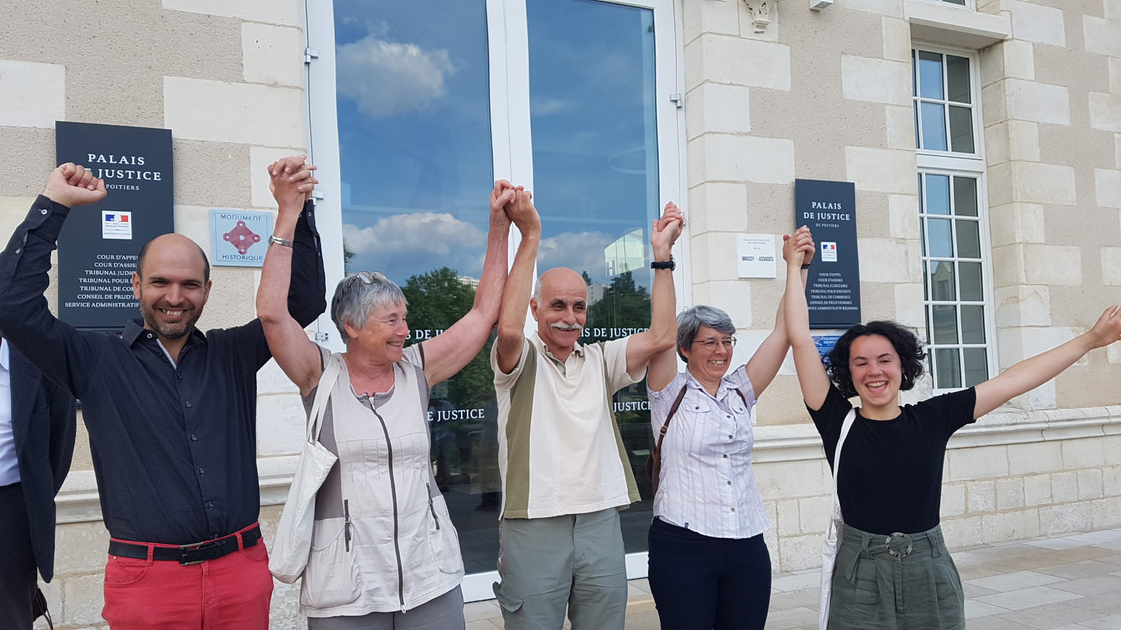 Cinq décrocheur·ses de portrait souriant et les bras en l'air devant le palais de justice de Poitiers