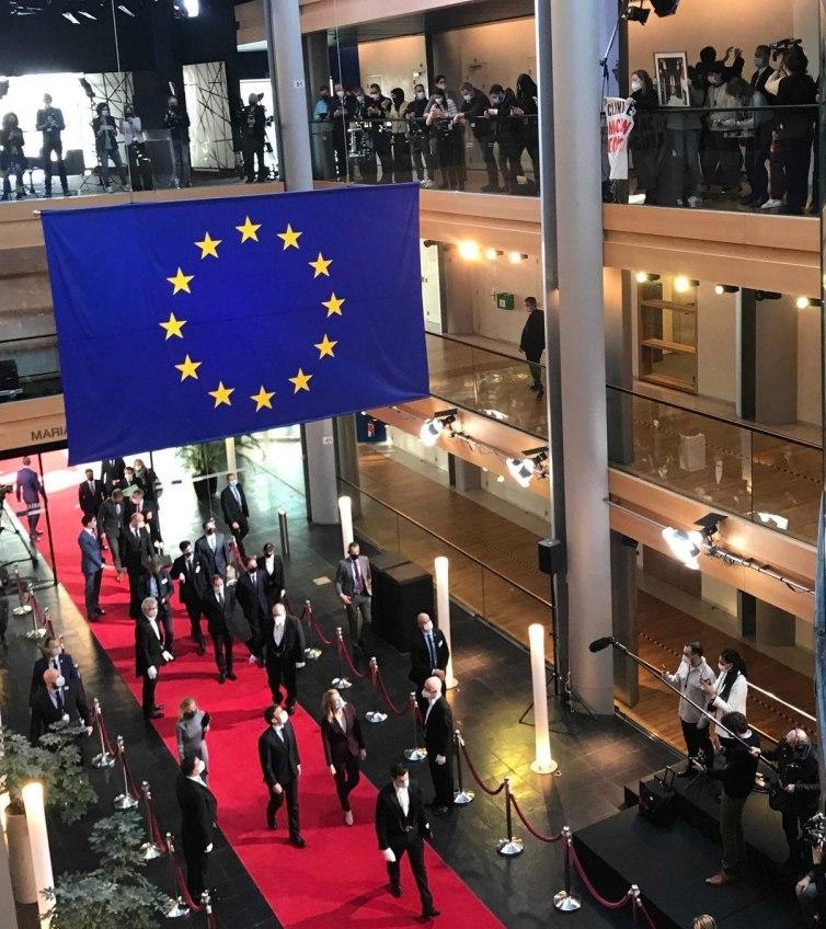 Le président Macron face à son portrait renversé dans le hall d'entrée du parlement