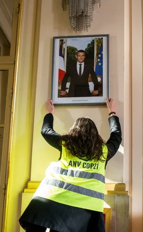 Une militante décroche une photo de D'Emmanuel Macron dans une mairie